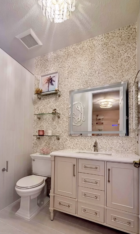 Powder room with mother-of-pearl wallpaper, custom vanity and monogram mirror